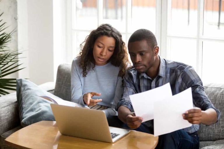 A black couple sit on a couch and work together to complete their DIY divorce documents.