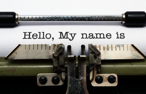 A close-up of a typewriter with paper and someone typing "Hello, My name is."