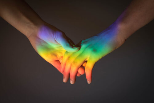 A close up of a gay couple holding hands.