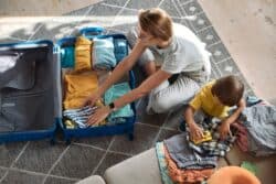 Mom packing her son's clothes in a suitcase for a visit to his co-parents' household.