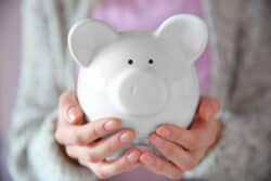 A women holds a piggy bank in her hands. Splitting retirement funds during a divorce can be a challenge.
