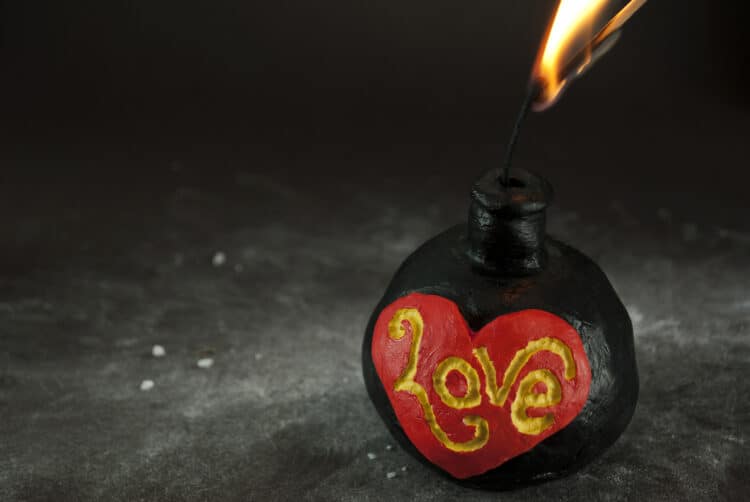 Old fashioned 'Positive Love' bomb with fuse being lighted, on dramatic dark underground.