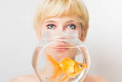 Portrait of a blonde woman with a goldfish in a bowl