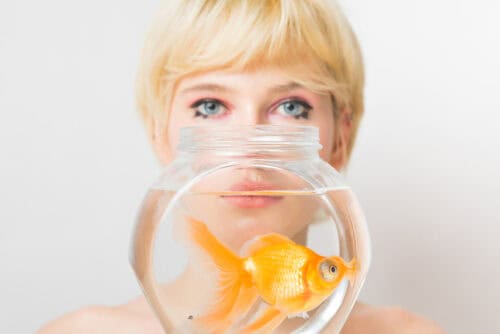 Portrait of a blonde woman with a goldfish in a bowl