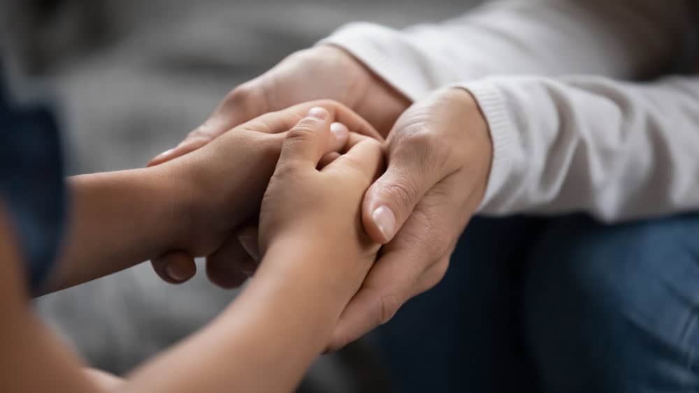 Close up mother supporting, touching adorable little daughter hands