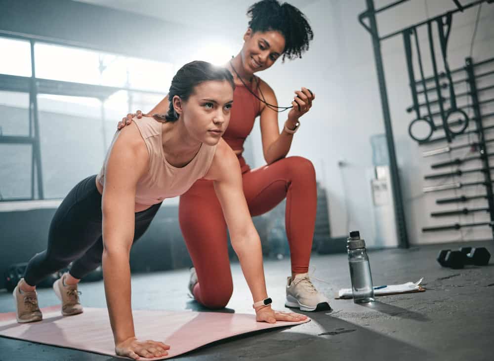 A personal trainer helps a your woman workout