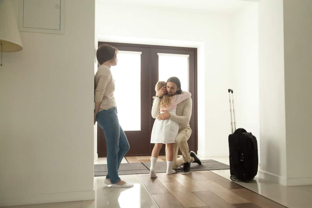 Little kid girl embracing dad leaving family moving out with travel suitcase