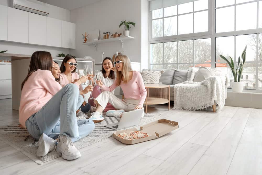 Young women with champagne and pizza at Hen Party in kitchen